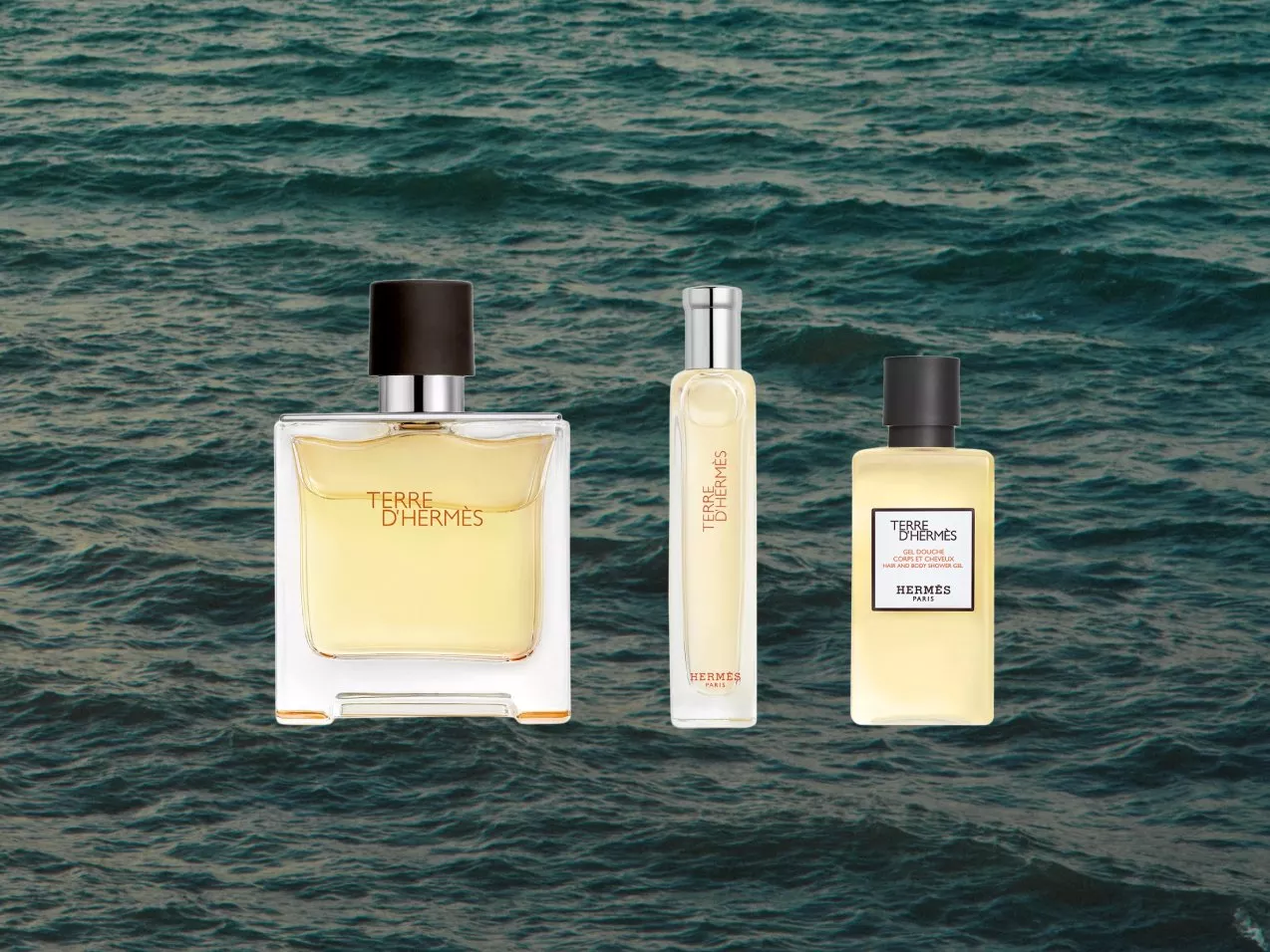 Terre d’Hermès fragrance set with eau de toilette bottle, travel spray and shower gel on ocean waves background
