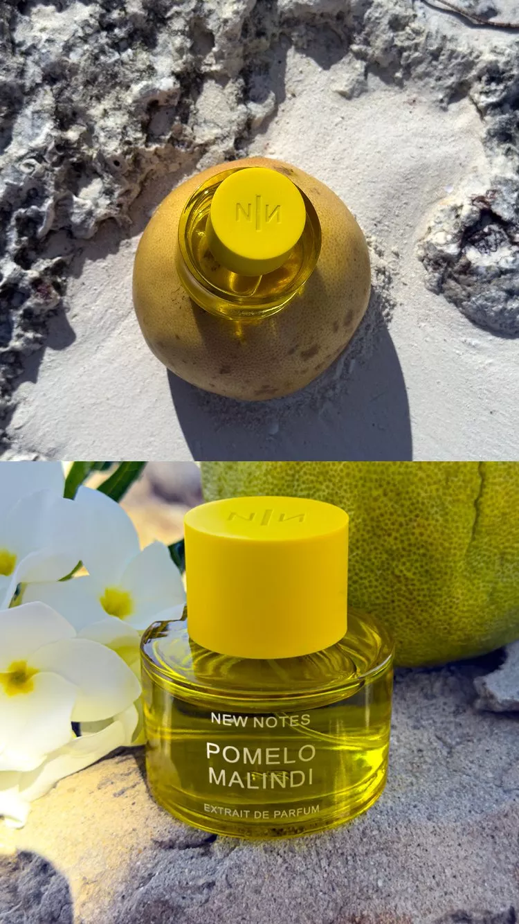 New Notes Pomelo Malindi extrait de parfum bottle with yellow cap beside citrus fruit and white flowers outdoors