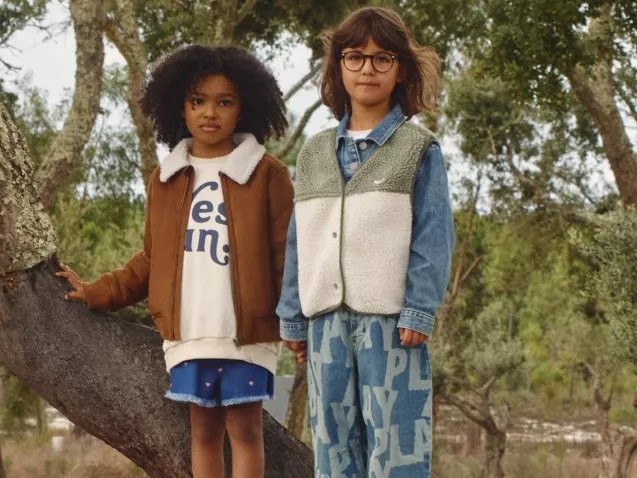 Two children in autumn outfits standing outdoors by trees, showcasing kids fashion jackets and layers