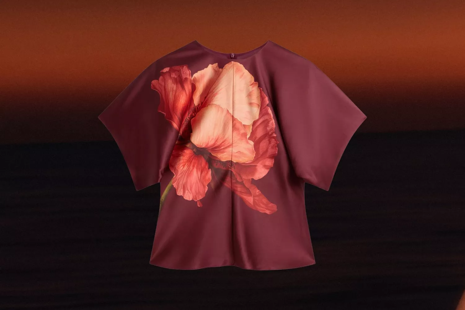 Burgundy short-sleeve blouse with large coral flower print, displayed on an ombre brown background.