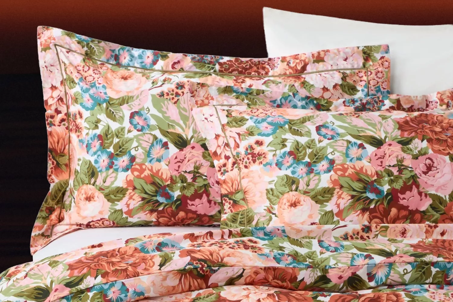 Floral bedding set with pastel rose and blue flower print pillows and duvet cover on a bed, close-up view