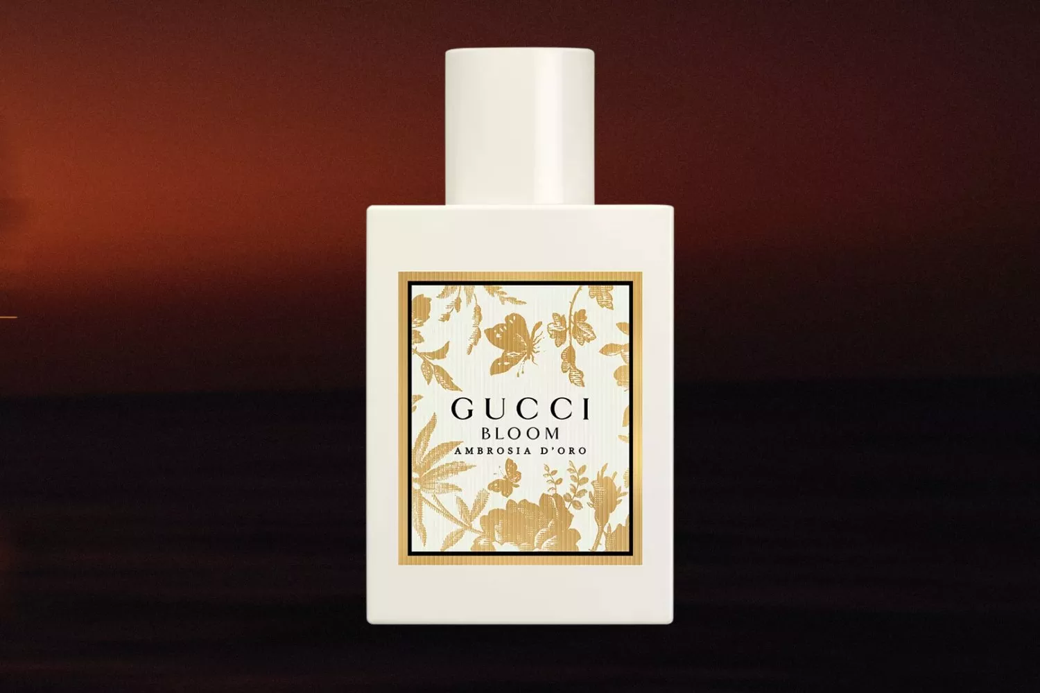 Gucci Bloom Ambrosia d’Oro perfume bottle with gold floral label on a warm, blurred background