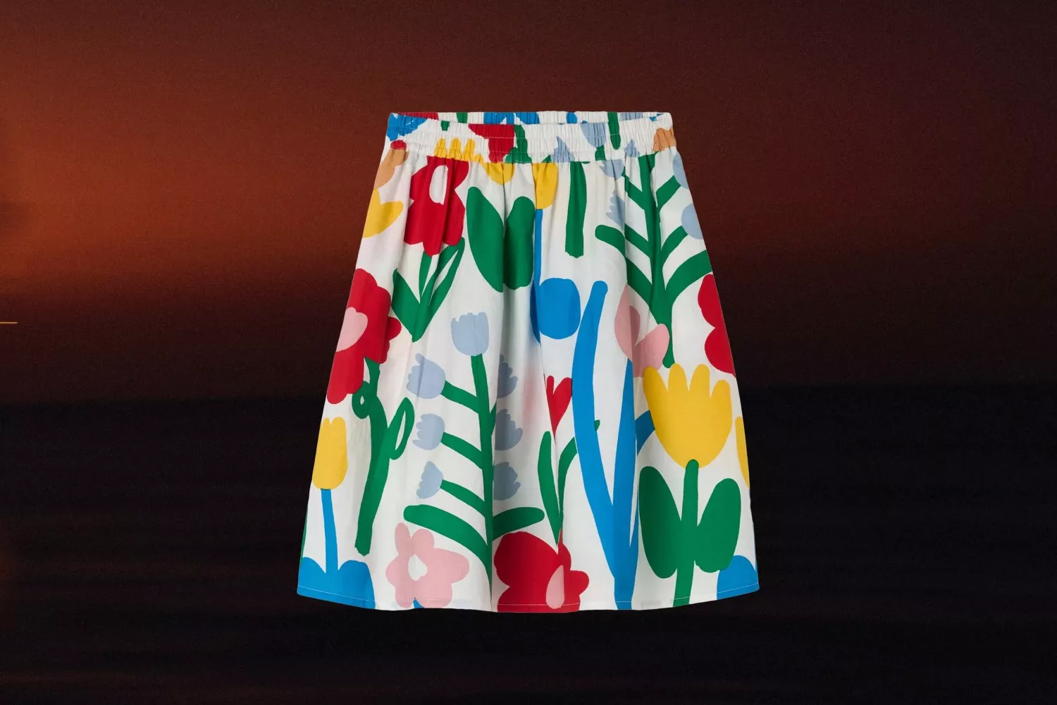 Colourful floral A-line skirt with elastic waist, bold botanical print, photographed on a dark gradient background