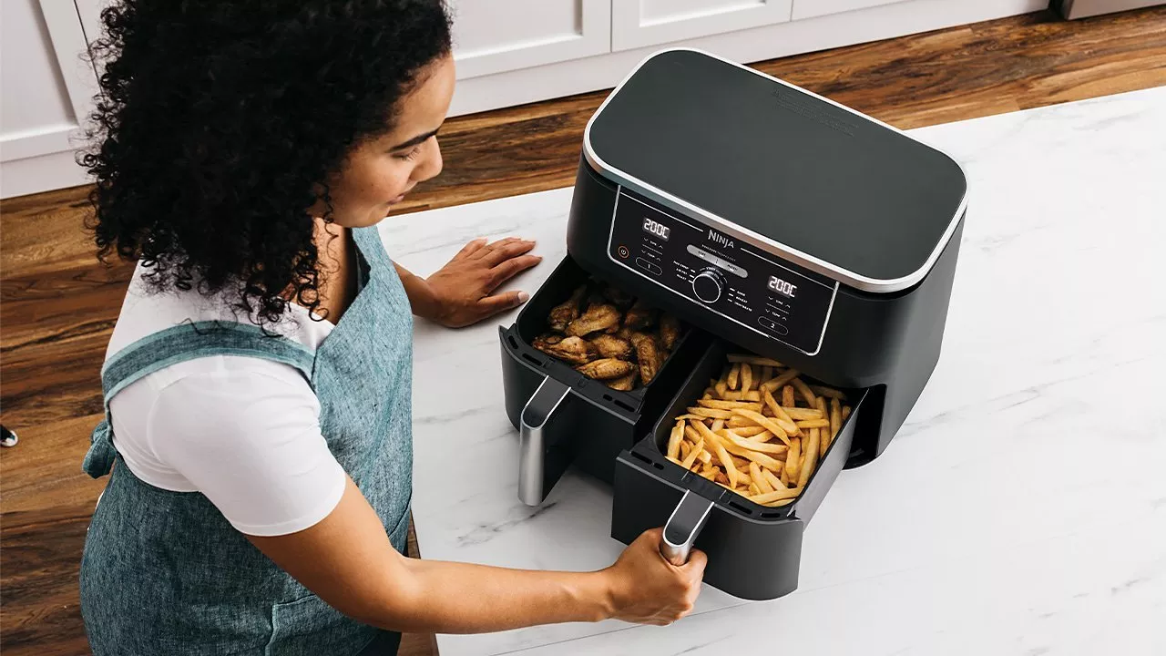 Bosch air fryer on kitchen counter with drawer open, cooking colourful vegetable and meat kebabs skewers