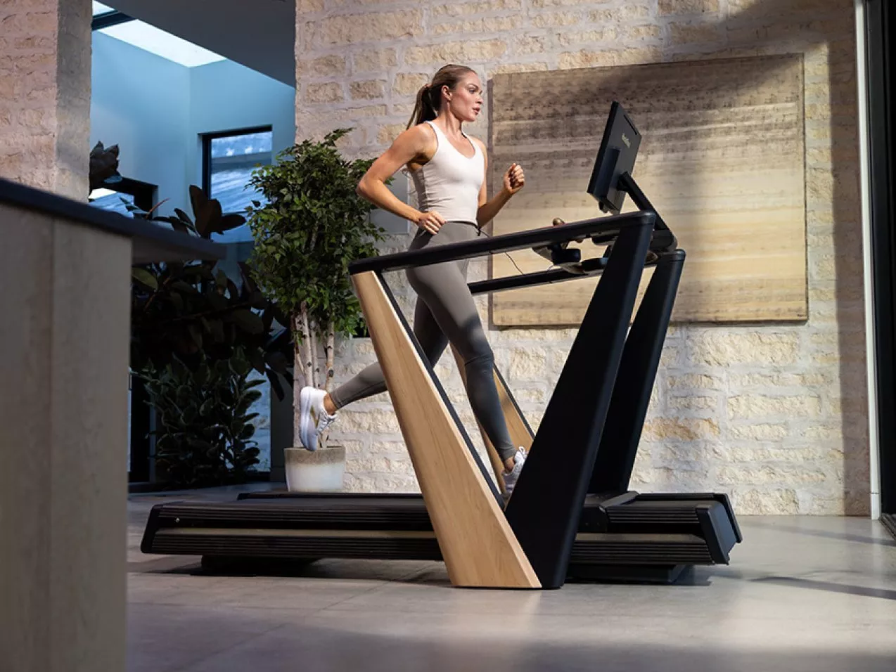 Woman walking on NordicTrack treadmill with touchscreen display, home gym cardio workout equipment on white background