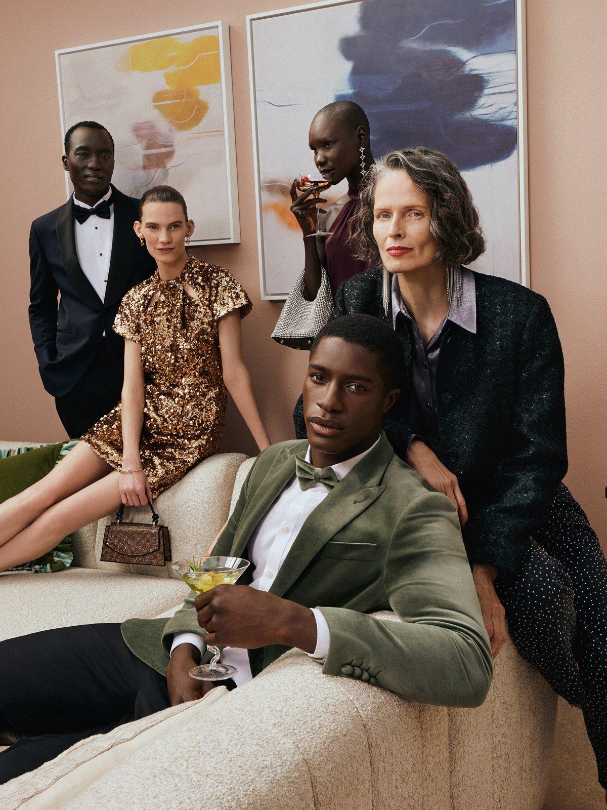 Image of men and women in partywear sitting around a sofa