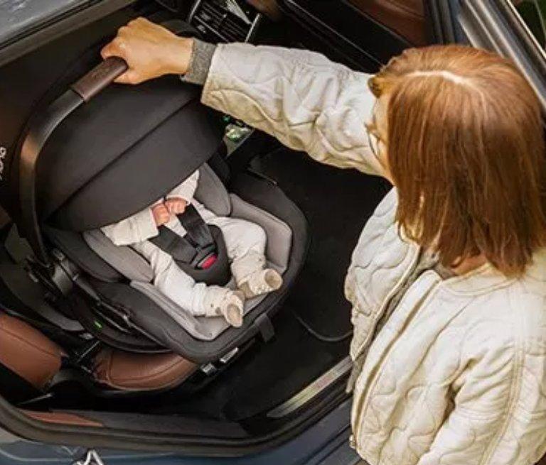 A banner showing women holding Baby carrier in a car.