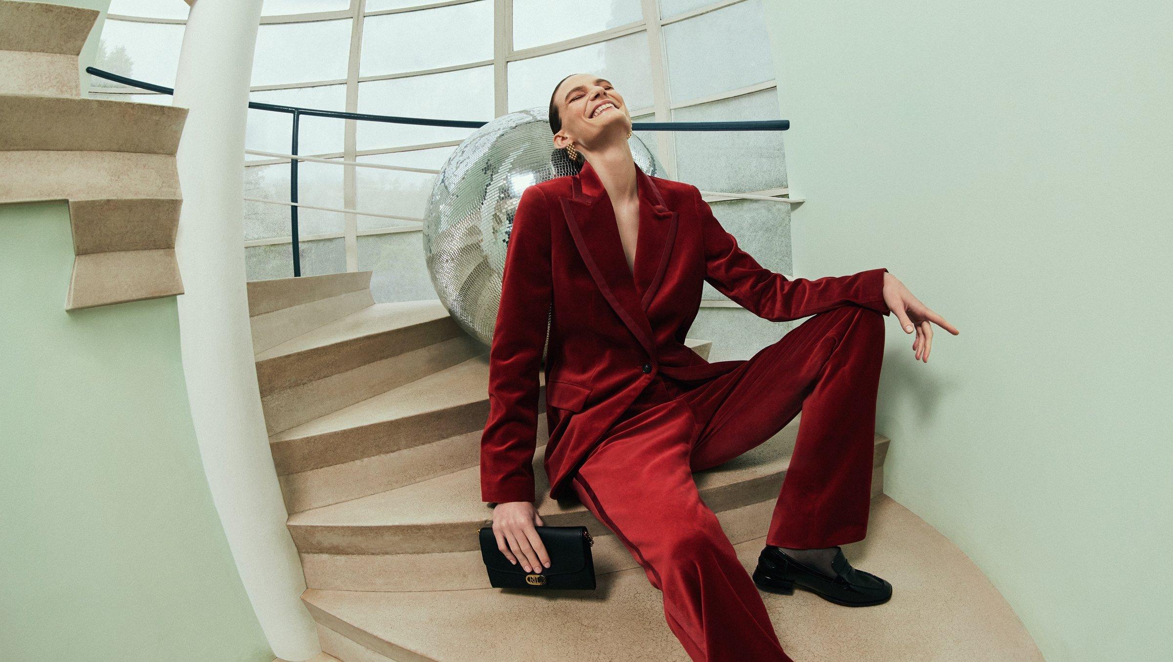 a lady sitting on some steps wearing a red velvet suit