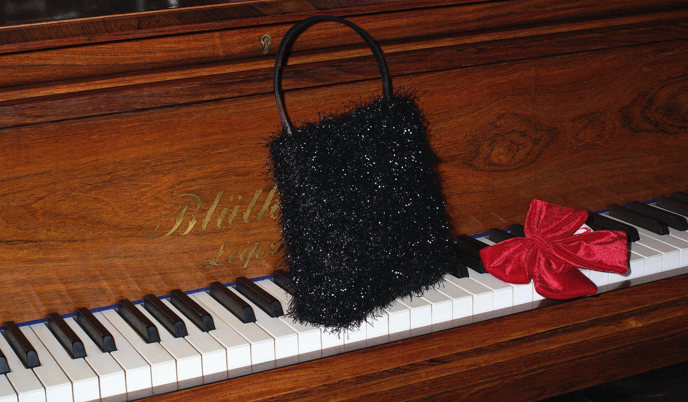 Image of a black sequin bag sitting on piano keys