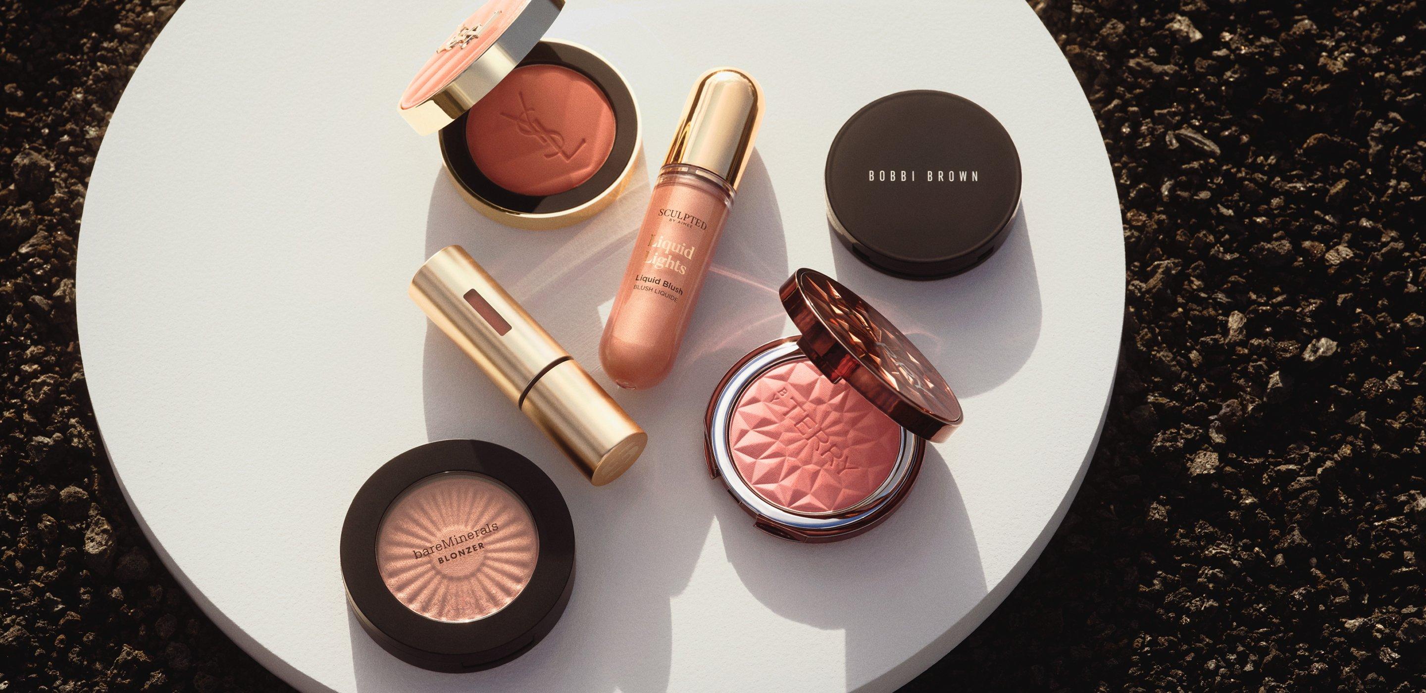 beauty products like on a white try sitting on black volcanic gravel