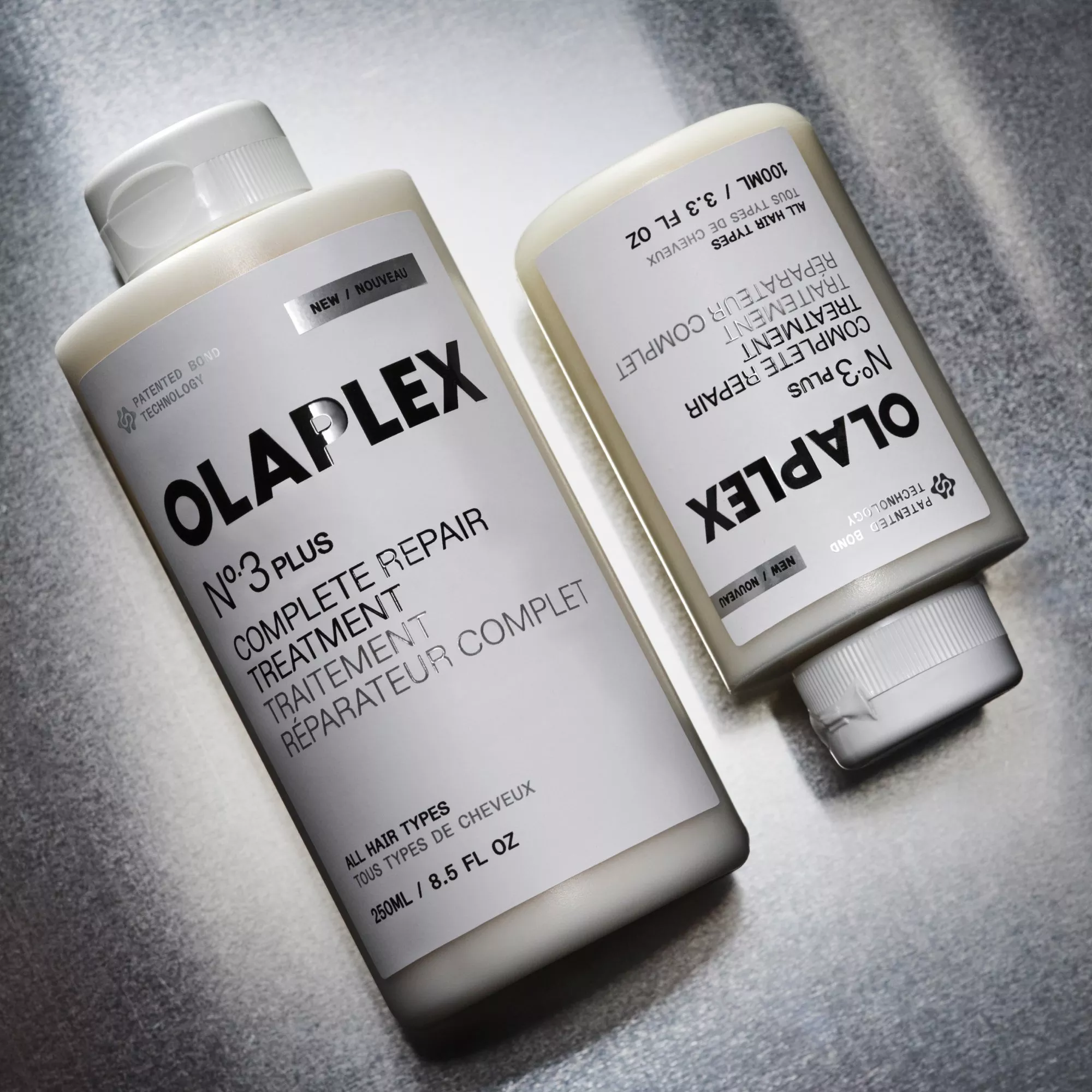 Olaplex No.3 Hair Perfector and No.0 Intensive Bond Building Treatment bottles on a grey textured surface