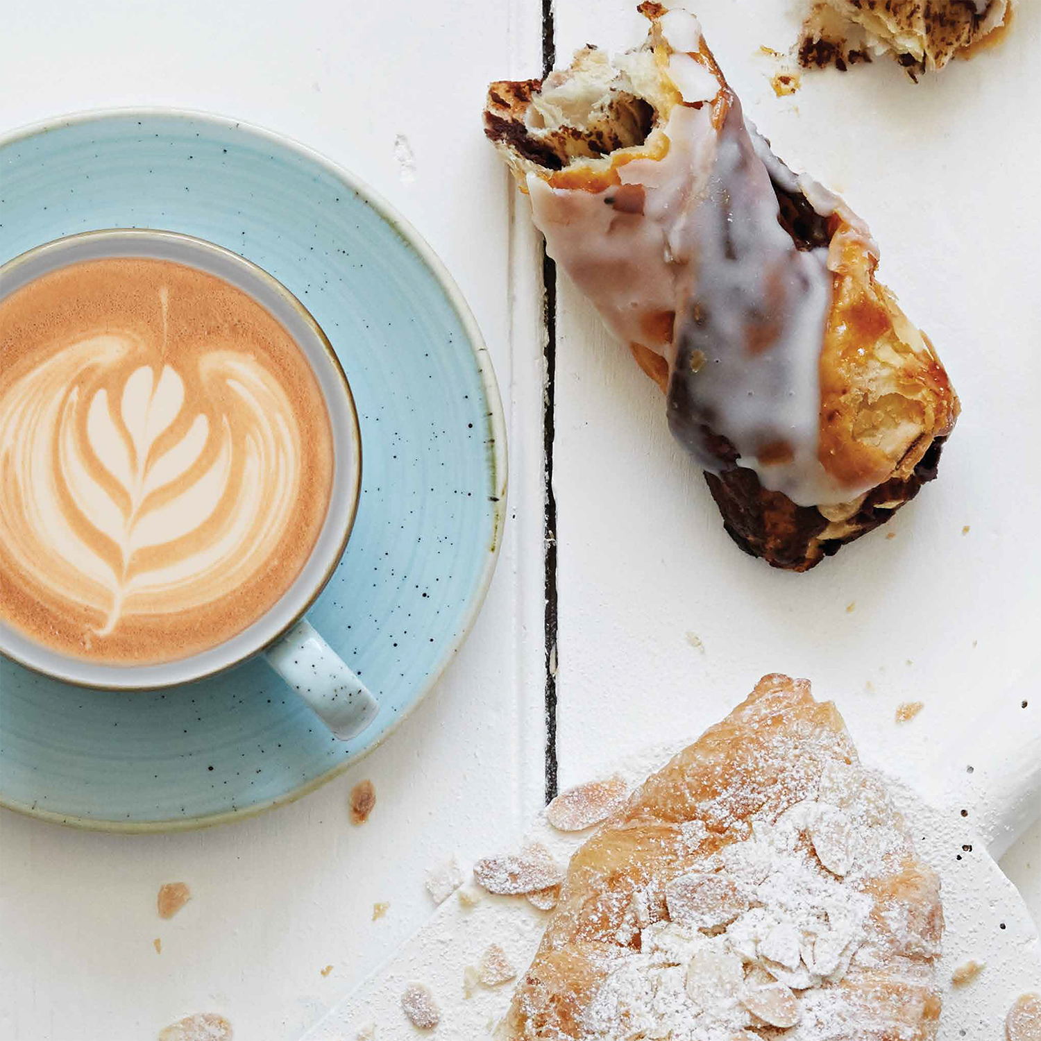 A shot from above of a coffe cup, almost croissant and chocolate twist