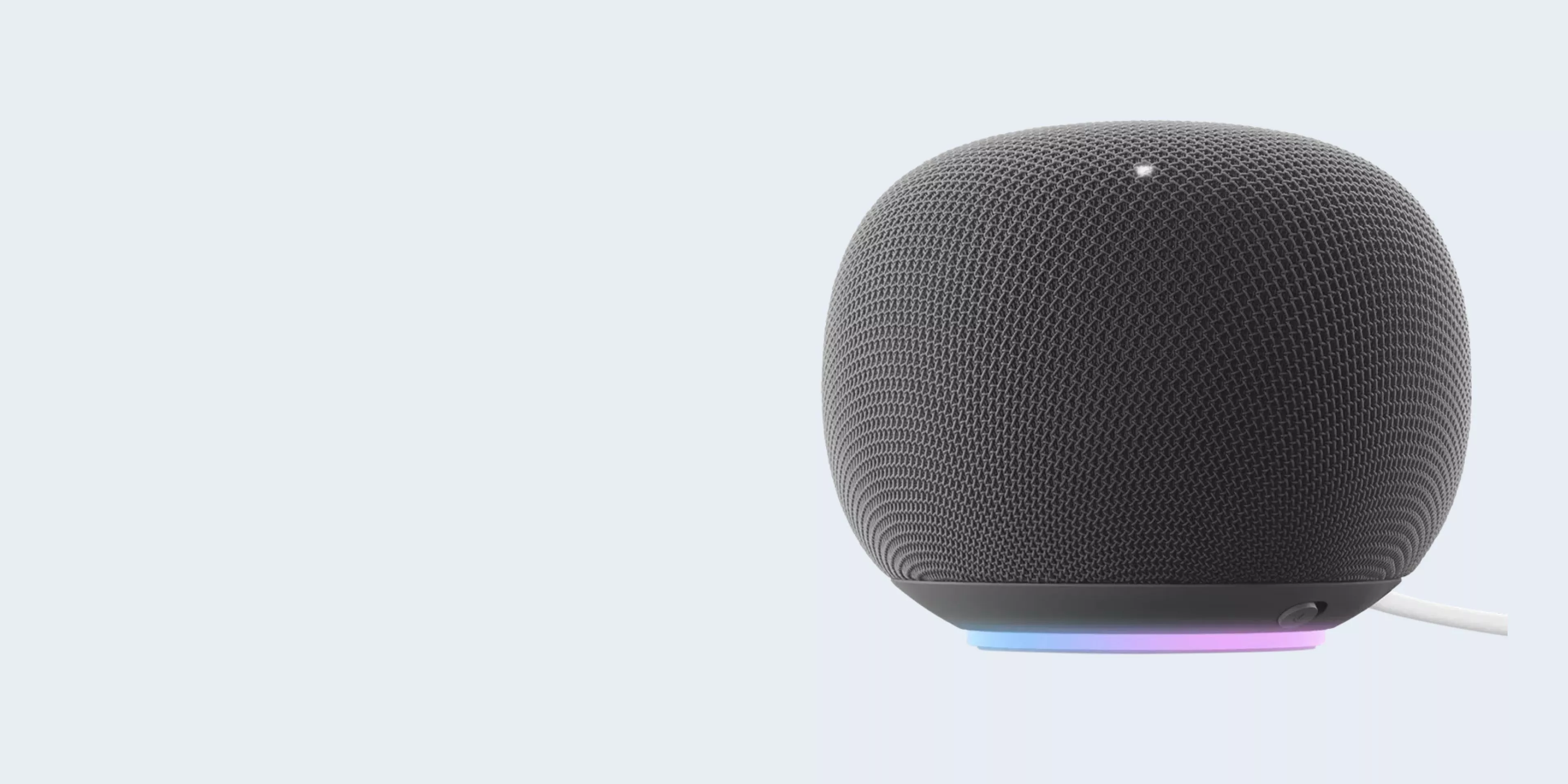 Black spherical smart speaker with fabric mesh and RGB light base, close-up product photo on pale background