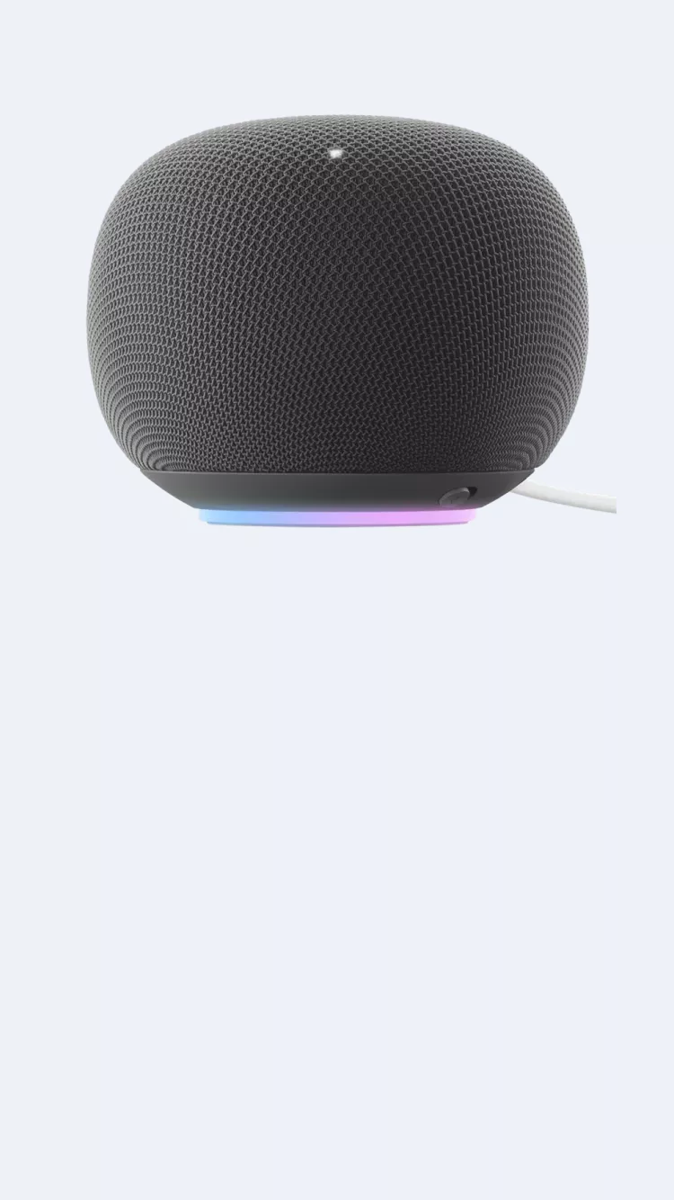 Black smart speaker with textured fabric grille, LED light ring base and power cable on a pale background