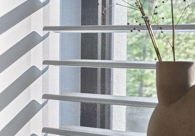 White blinds on a window with a vase on the windowsill
