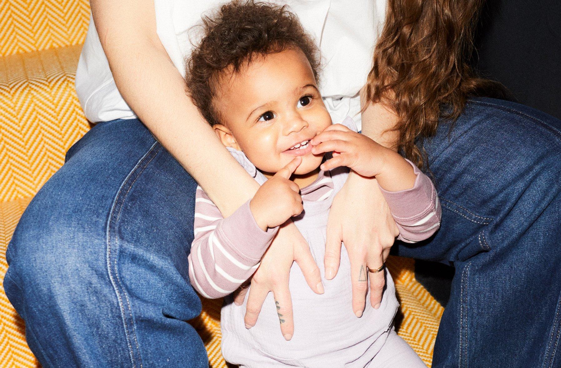Image of a baby lying on the floor inbetweens it's mothers legs