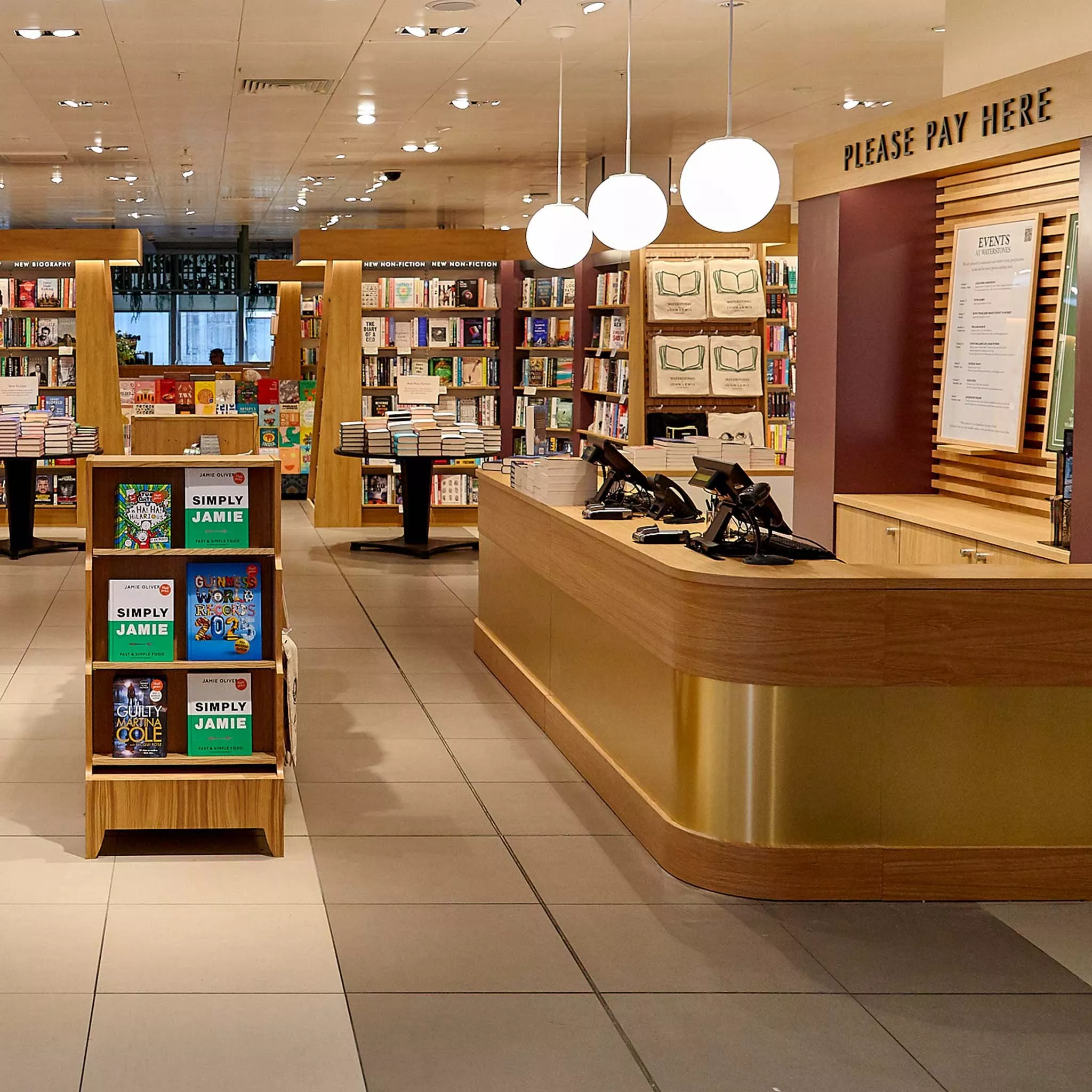 Modern bookstore interior with wooden shelves, books neatly displayed, and a stylish checkout counter.