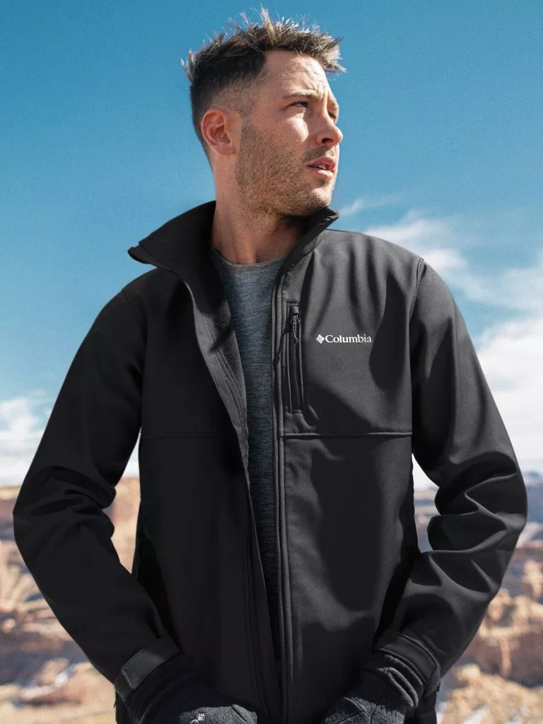 man wearing a columbia brand jacket standing on a mountain