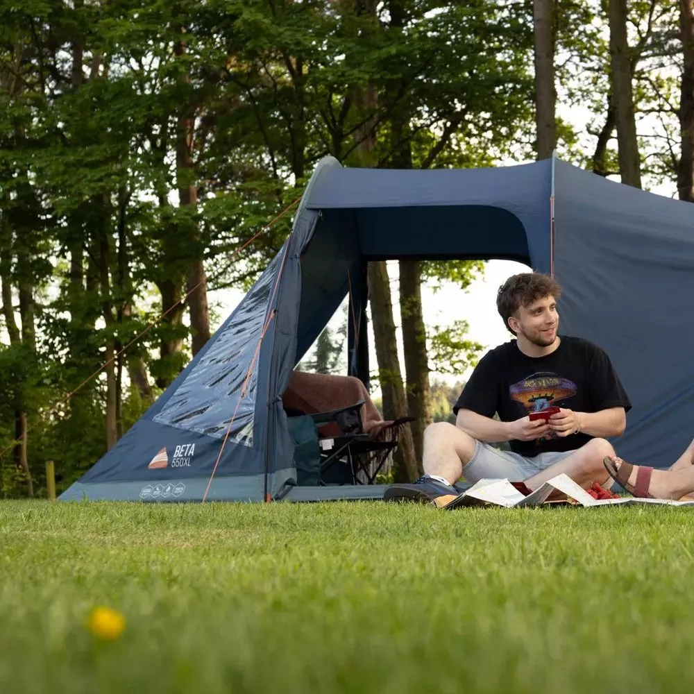 man sitting on grass in front of an open blue tent