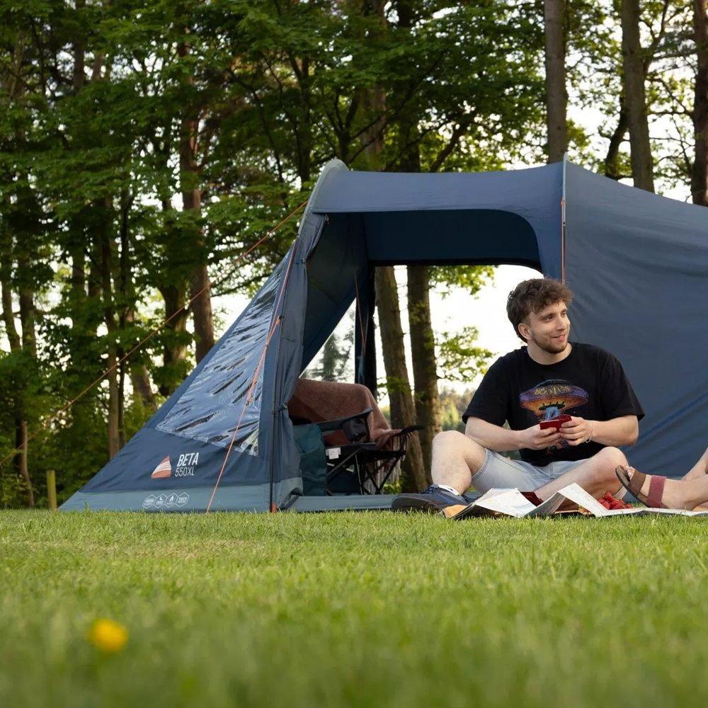 young man sitting outside a tent in a field