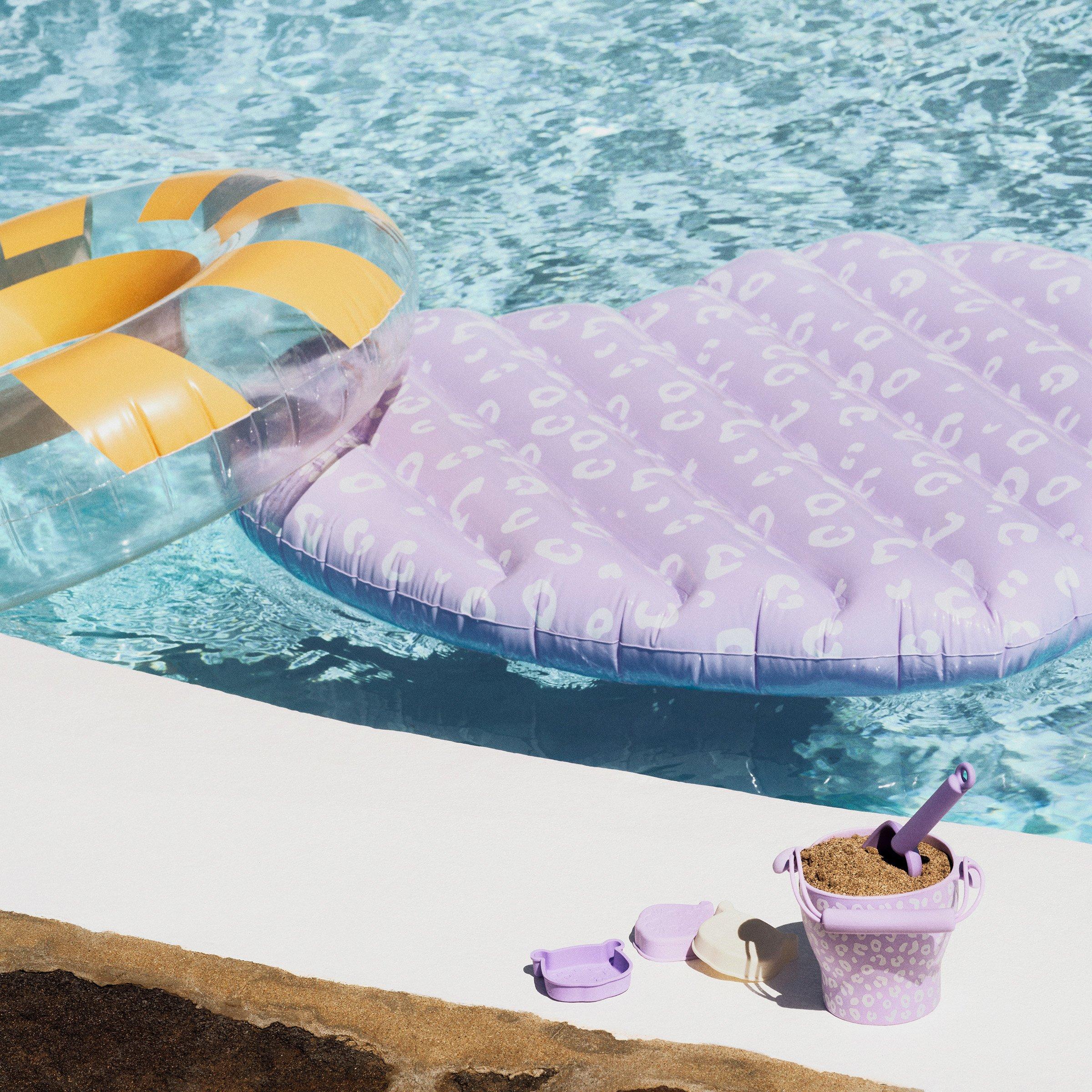 Child's bucket and spade on pool side, and an inflatable ring and float in the pool