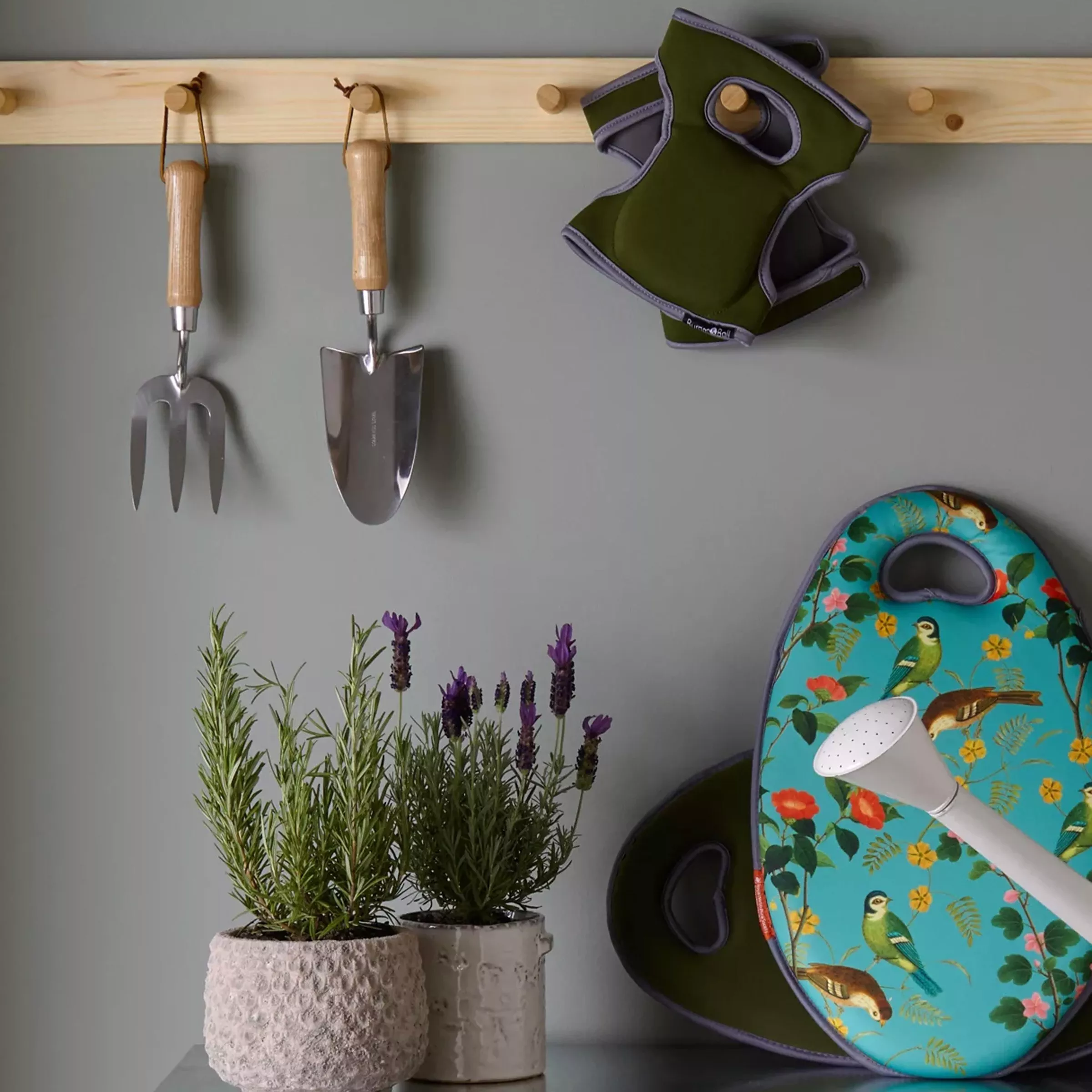 Garden tools hanging on a wall with herb pots