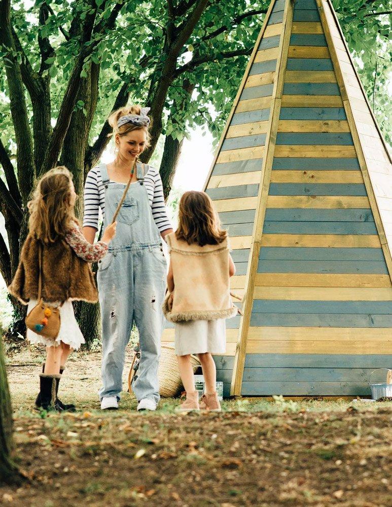 Children and adult outside wooden playhouse