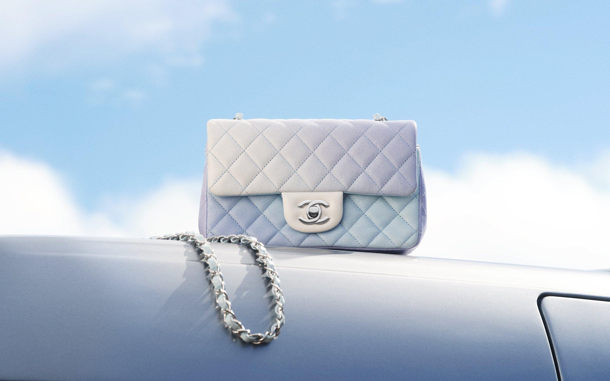 Image of a vintage chanel bag sitting on-top of a car with a blue sky behind it