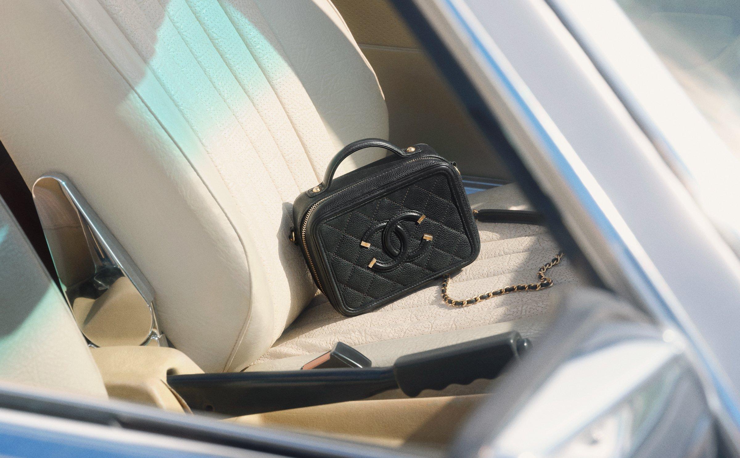 Image of a vintage Chanel handbag sitting inside a vintage car on the car seat, shot through the window