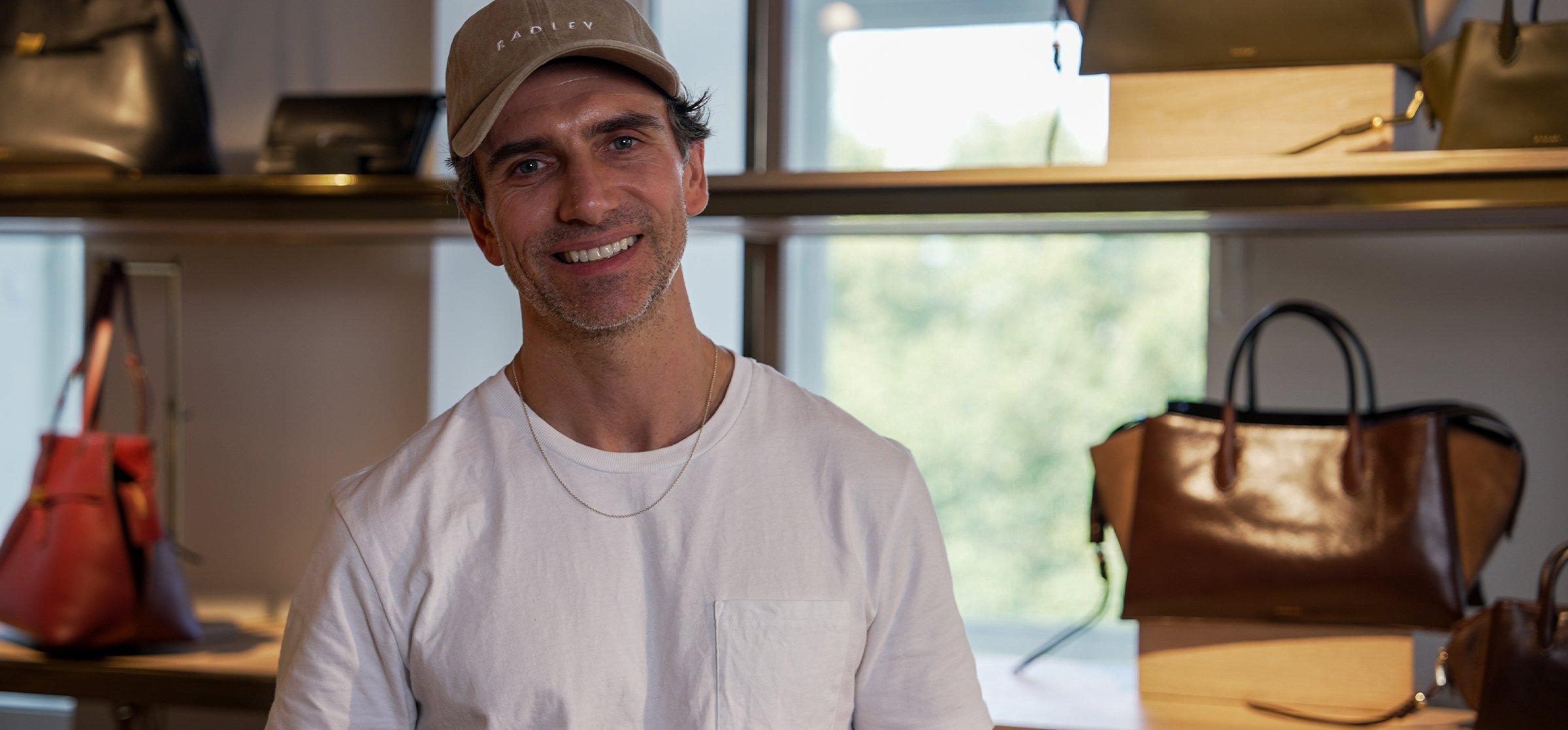 Radley's Design Director Fernando Soriano Iglesias standing infront of Radley hand bags