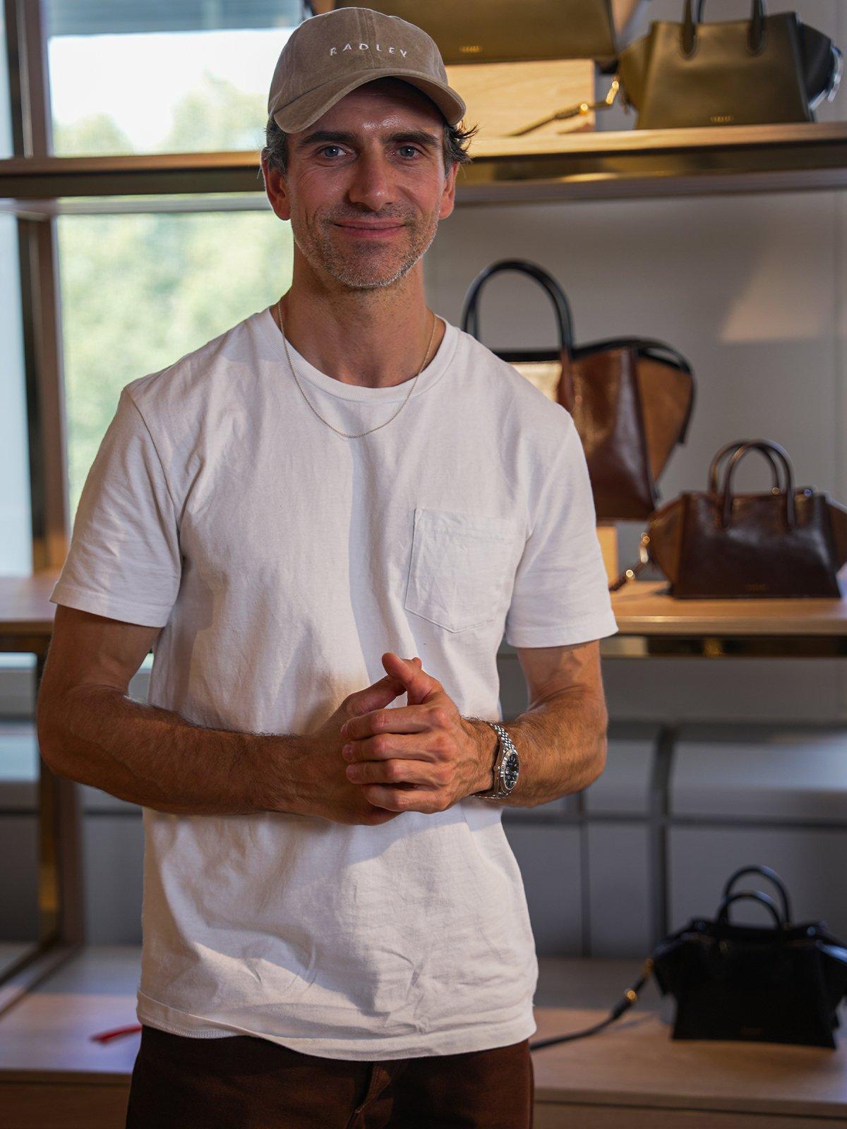 Radley's Design Director Fernando Soriano Iglesias standing infront of Radley hand bags