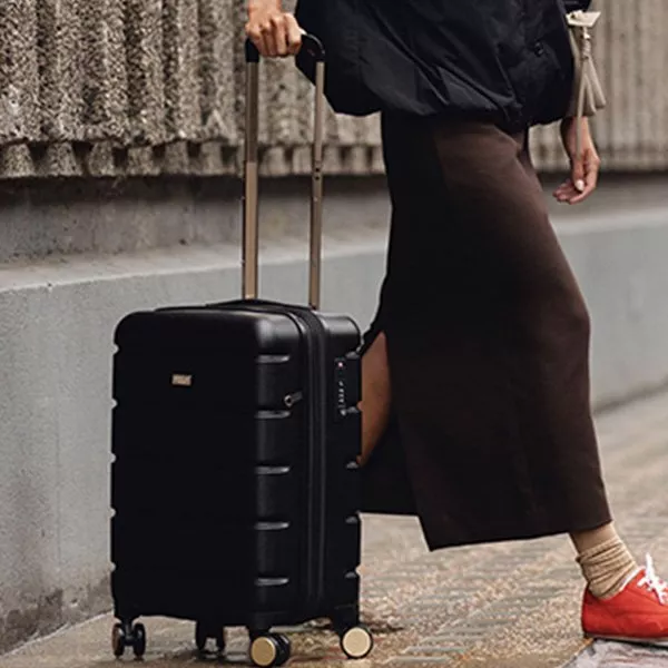 Lady pulling a black medium suitcase with  gold extendable handle