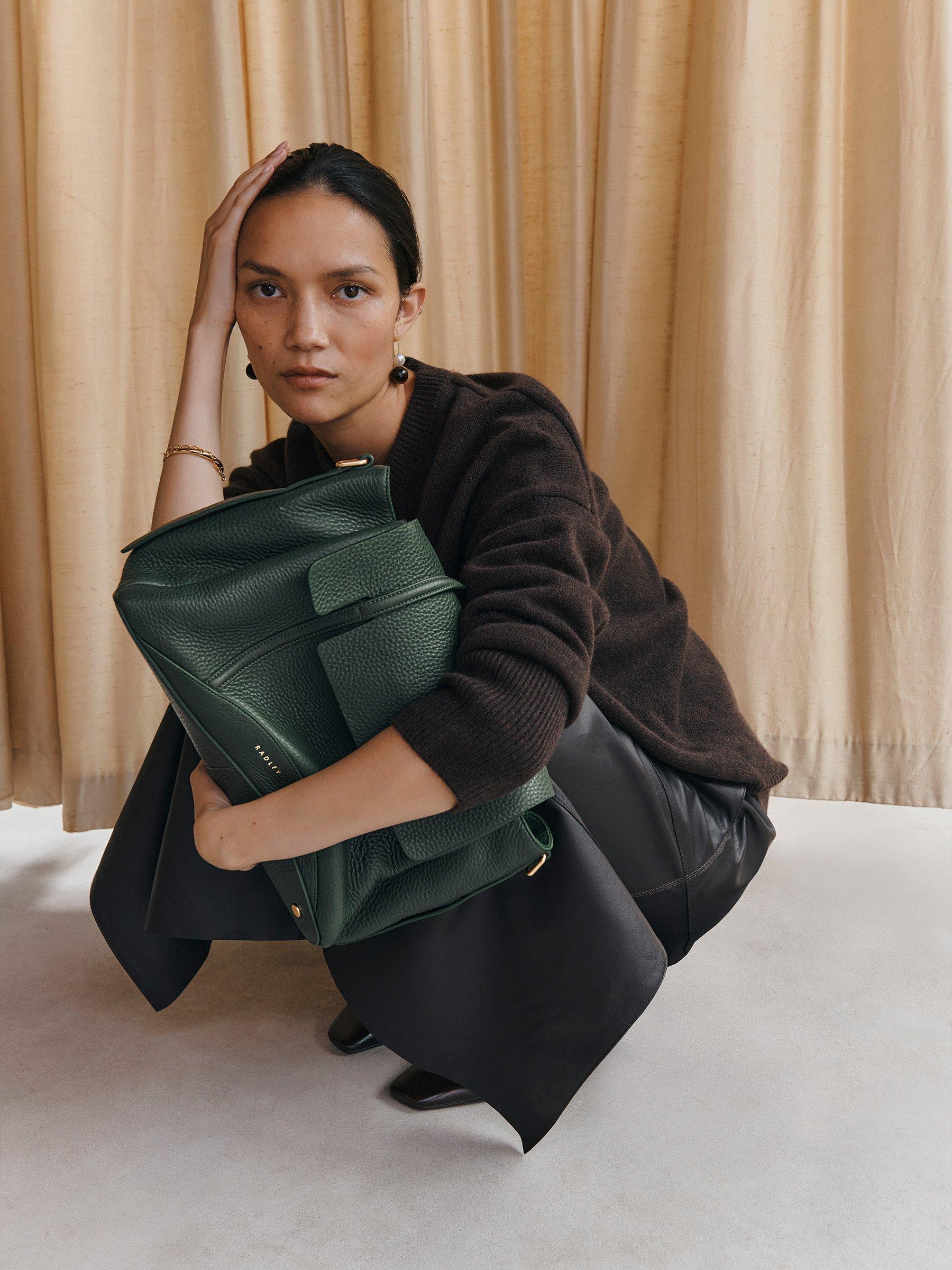 Woman crouching holding deep green Chancery grab bag
