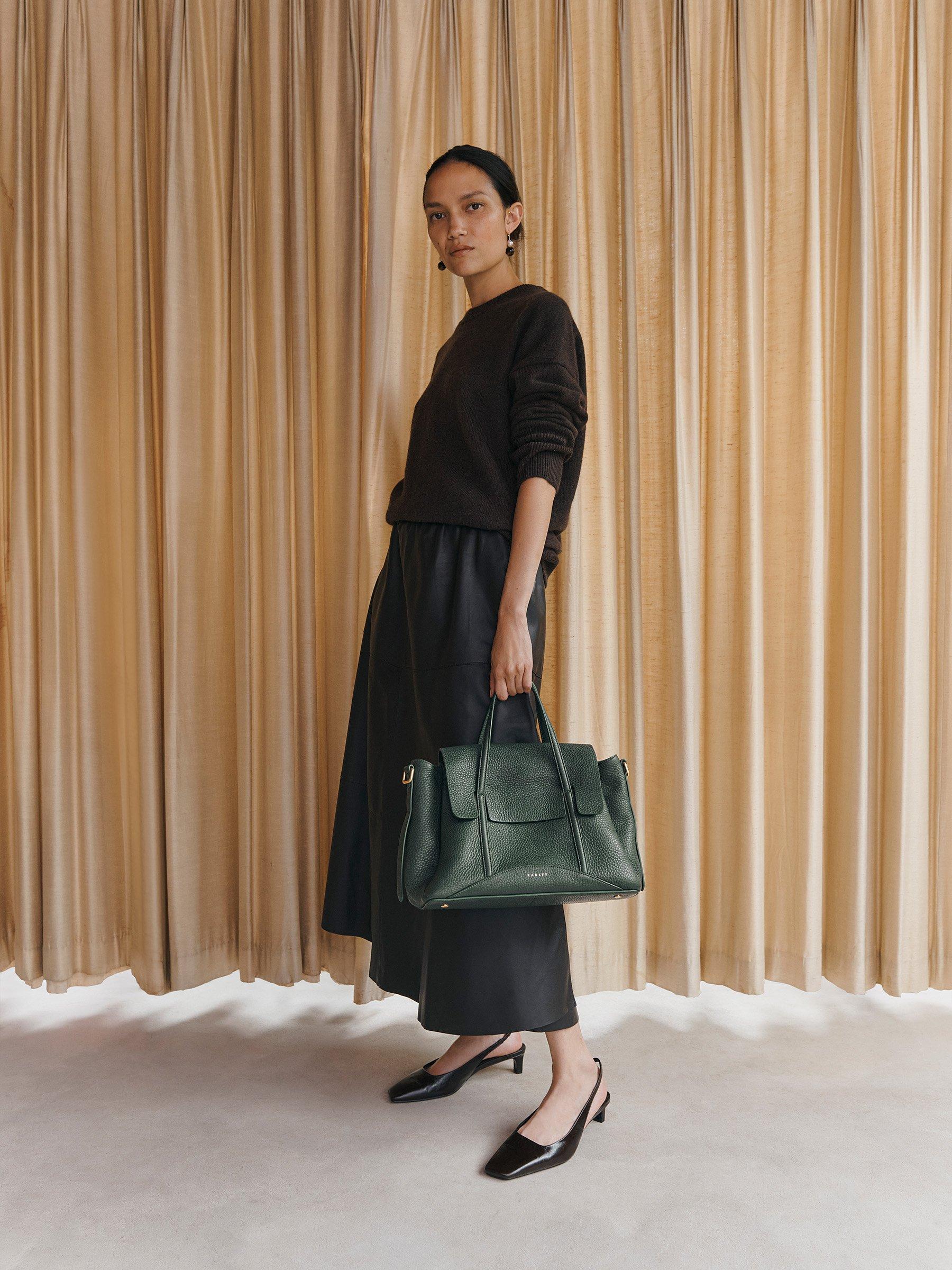 Woman standing holding deep green Chancery grab bag