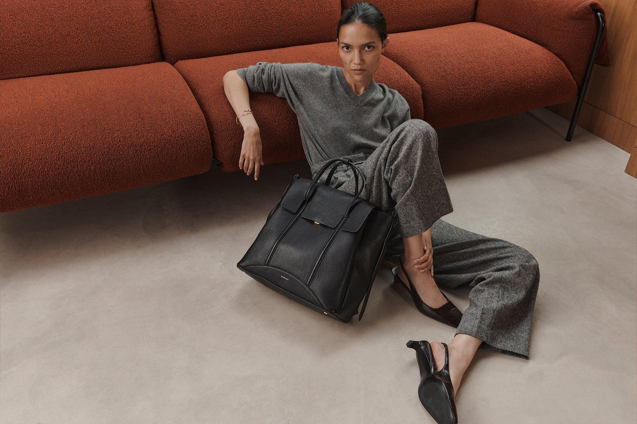 Woman sitting on floor holding black Chancery backpack