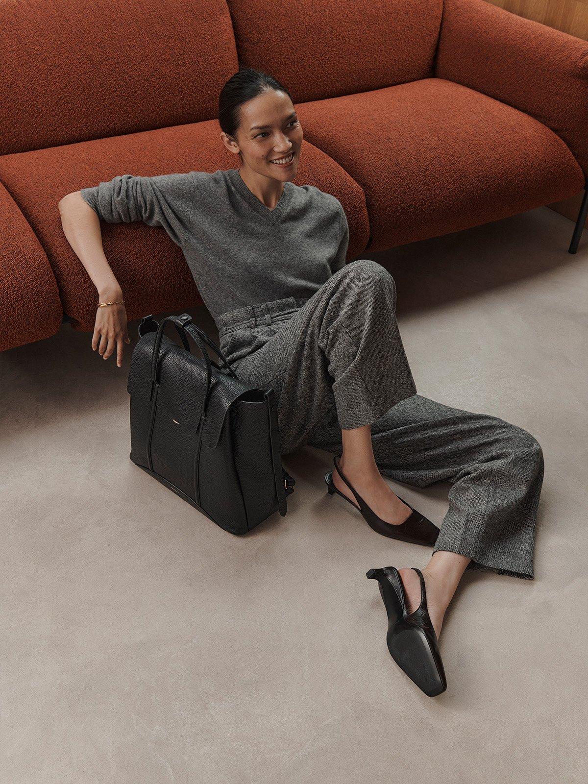 Woman sitting on floor holding black Chancery backpack