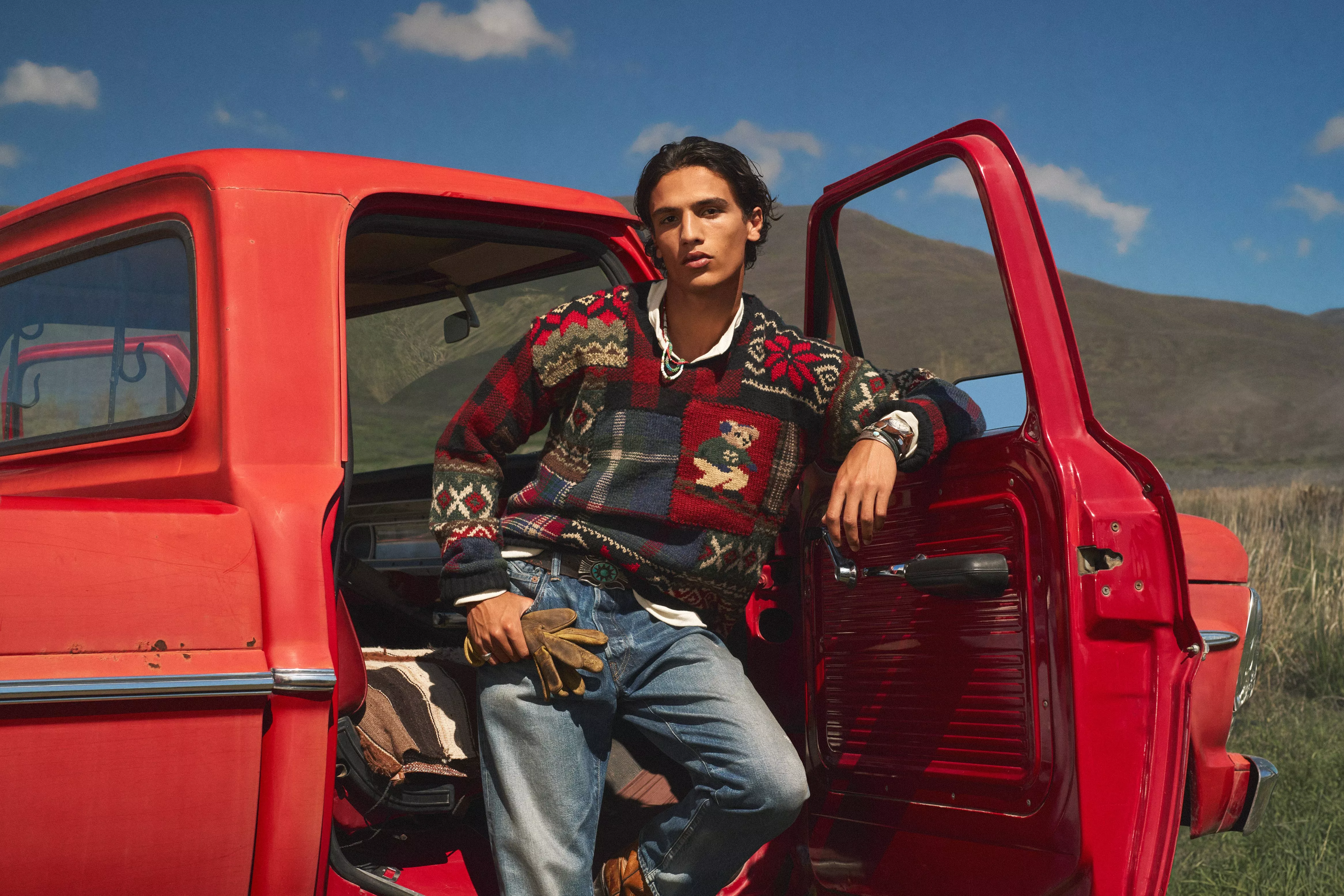 Man standing in door frame of a red truck wearing Polo Ralph Lauren