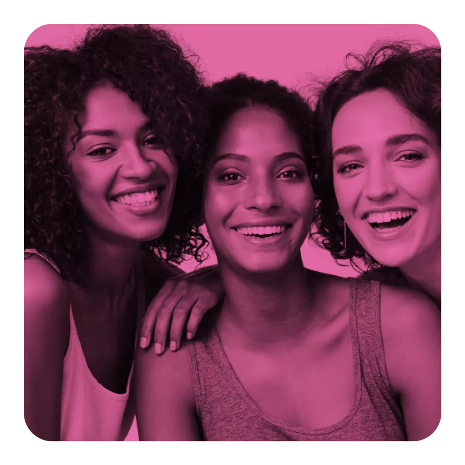 Three women smiling brightly, posing closely together, tinted in pink.