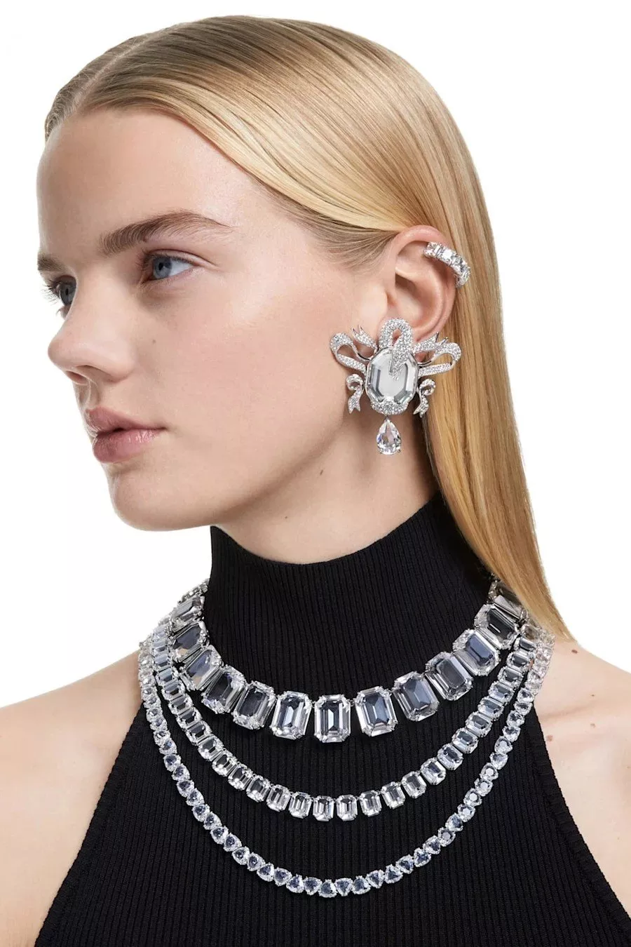 Model wearing luxury diamond statement earrings, ear cuff and layered crystal necklaces on a white background