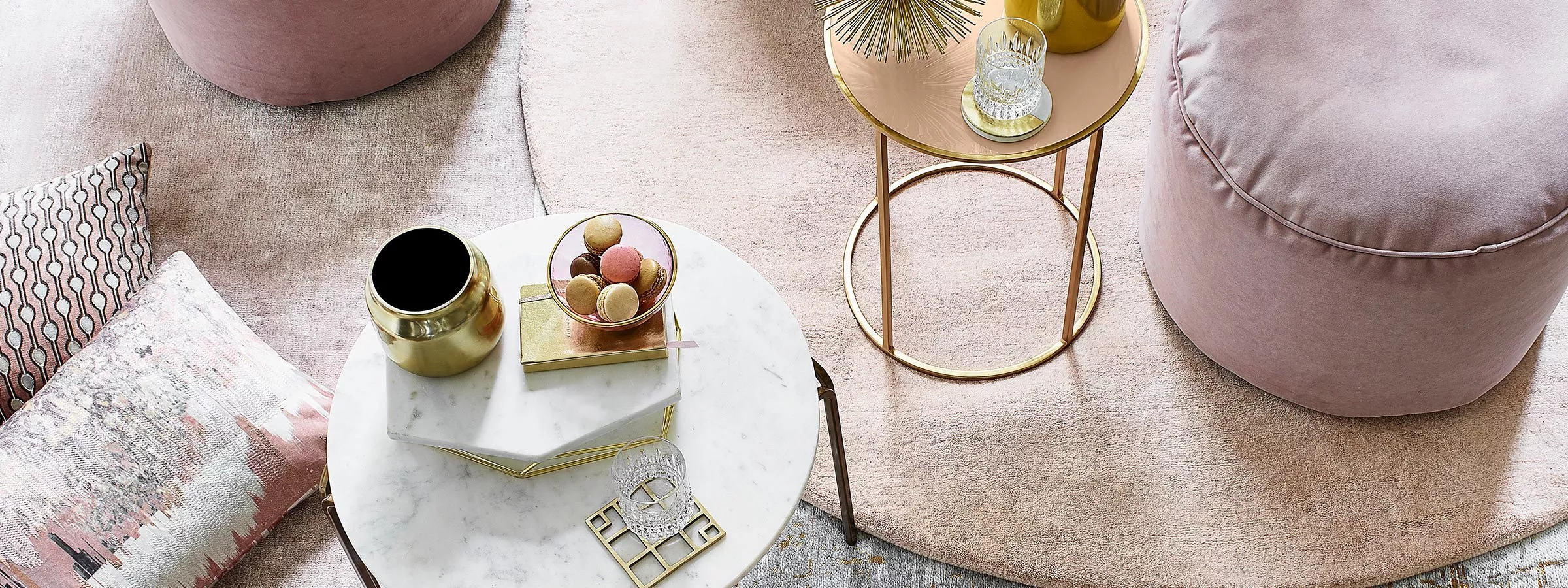 Modern blush living room with marble coffee table, gold side table, velvet pouffe and macarons on tray