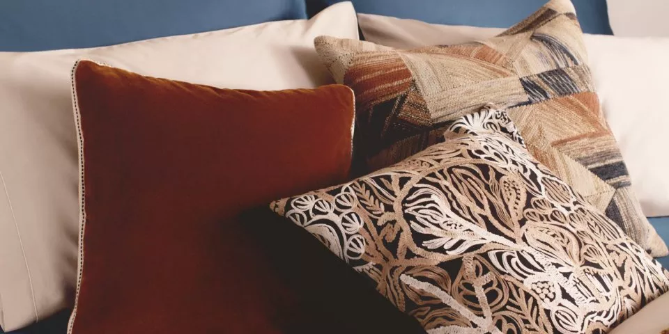 Decorative throw cushions on a sofa, featuring velvet rust, geometric tapestry and floral patterned covers