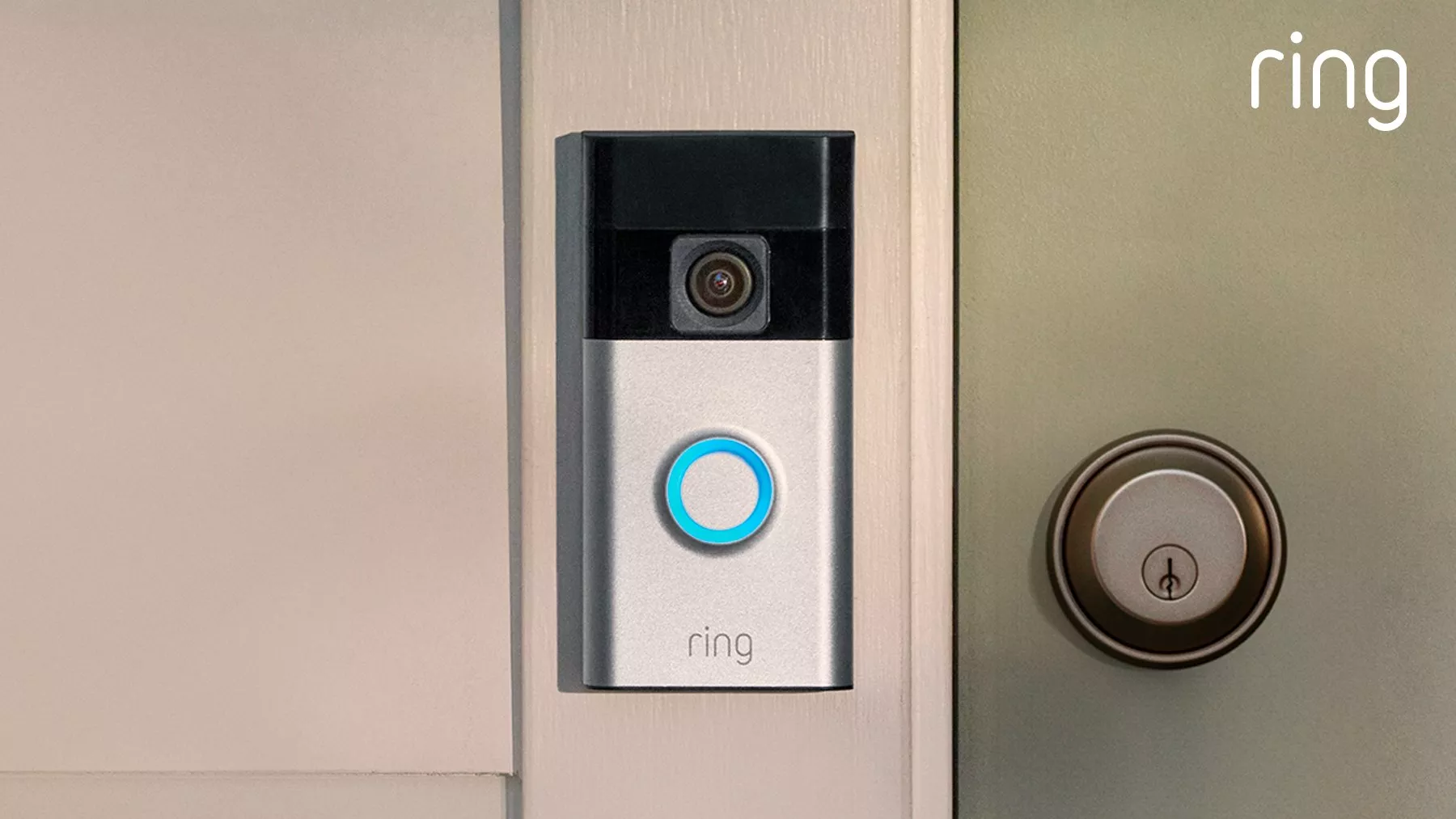 Ring video doorbell mounted on front door frame, showing camera lens and illuminated button beside smart lock