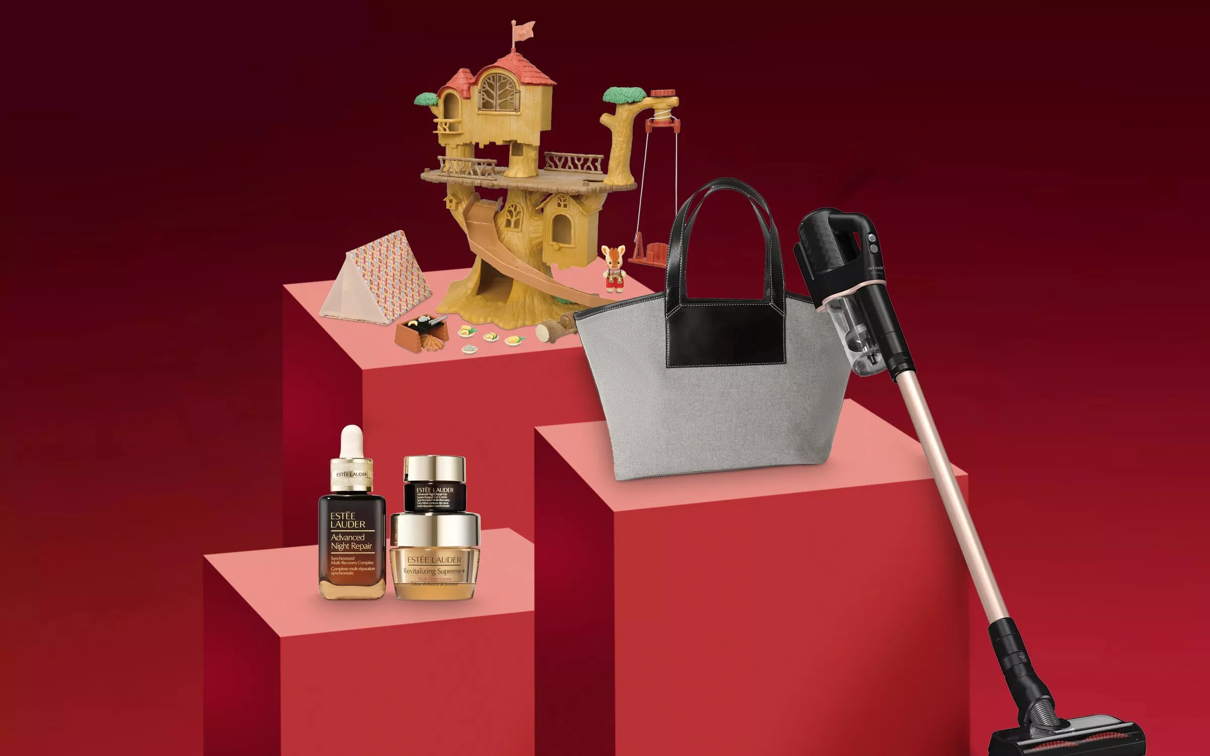 A collection of gift items including an Estée Lauder skincare set, a grey tote bag, a handheld vacuum, and a children's treehouse toy set arranged on tiered red blocks.