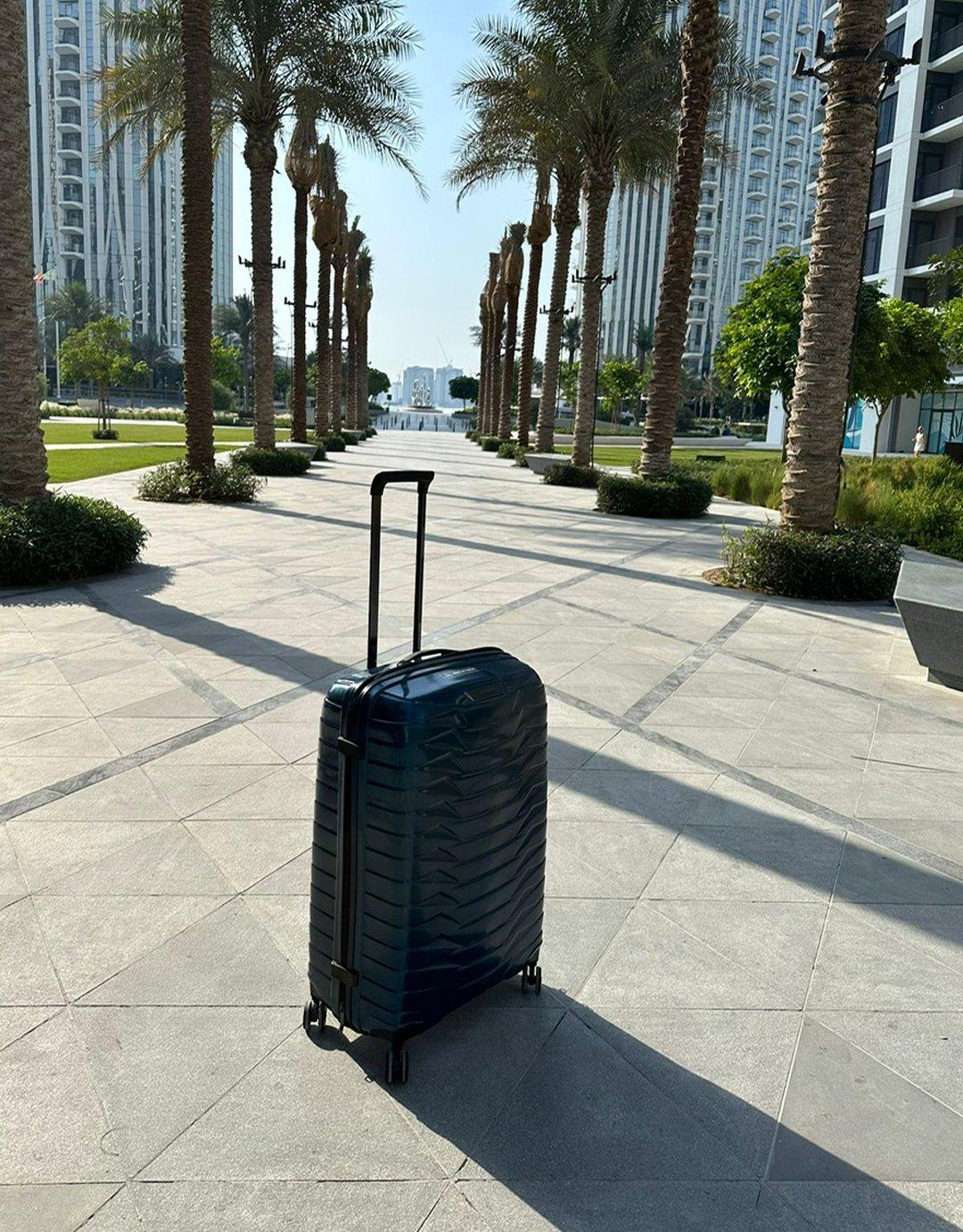 Image of a Samsonite suitcase outside a hotel with palm trees behind it