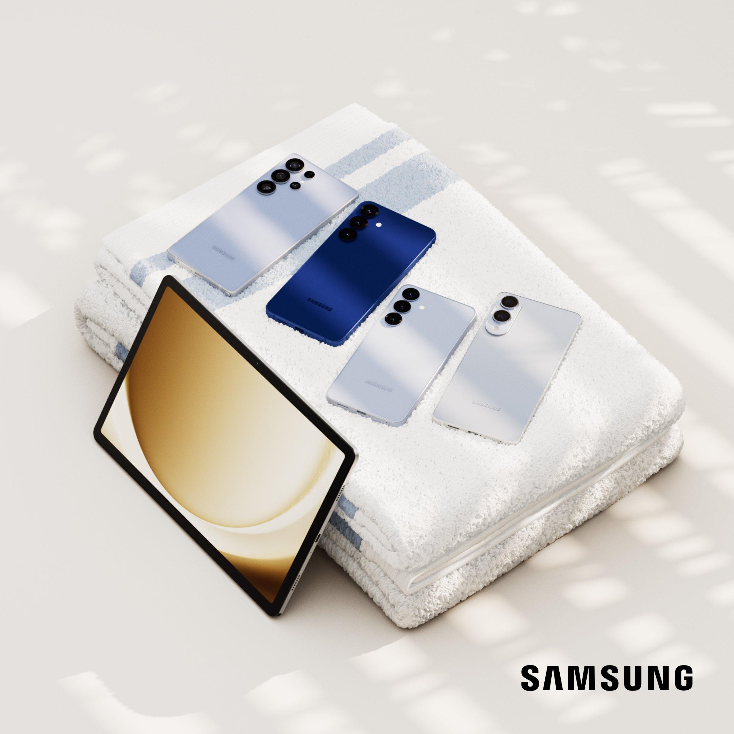 Samsung smartphones and a tablet displayed on white towels under soft lighting