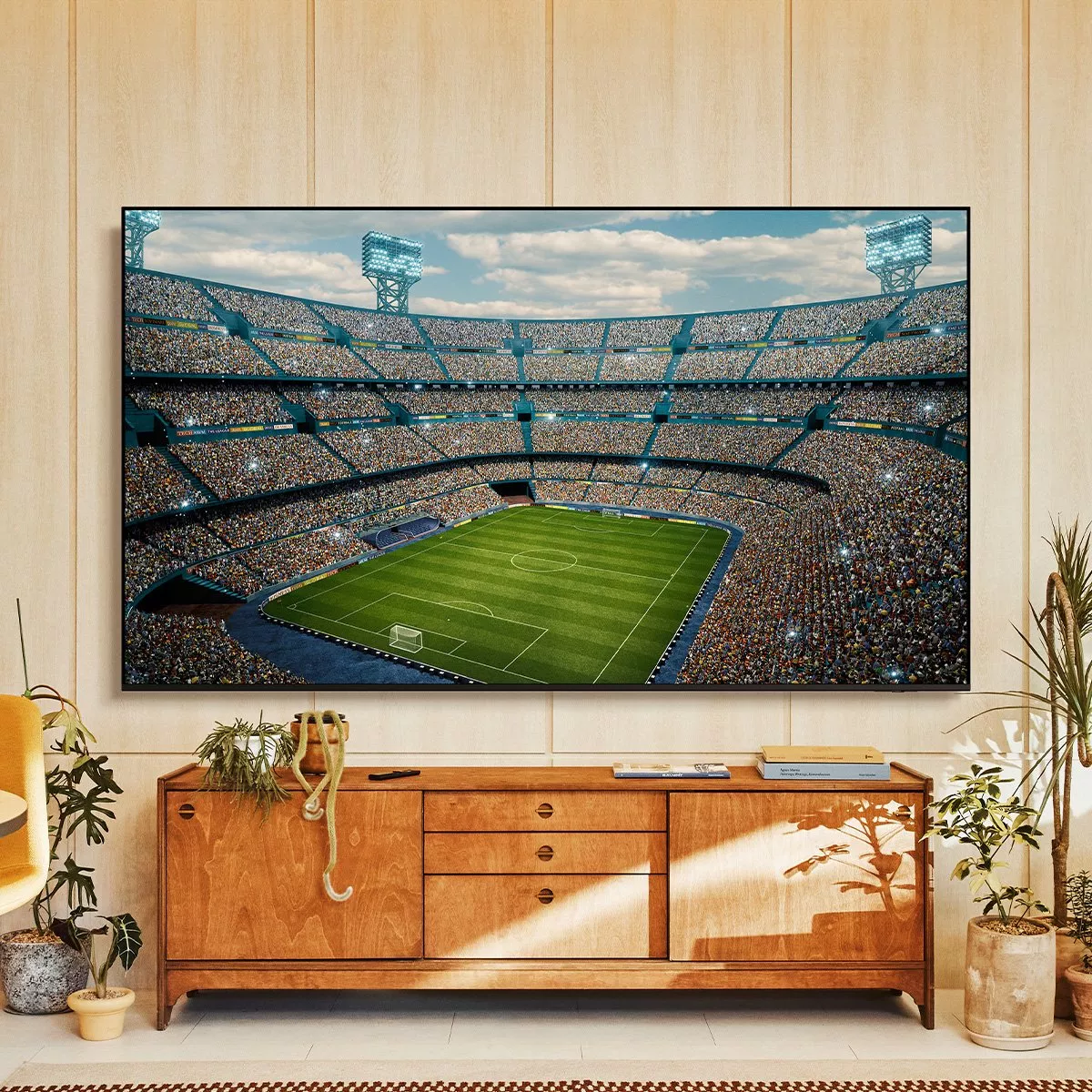 Modern living room with large TV gaming screen on wooden sideboard, beside fireplace, guitar and lamp.