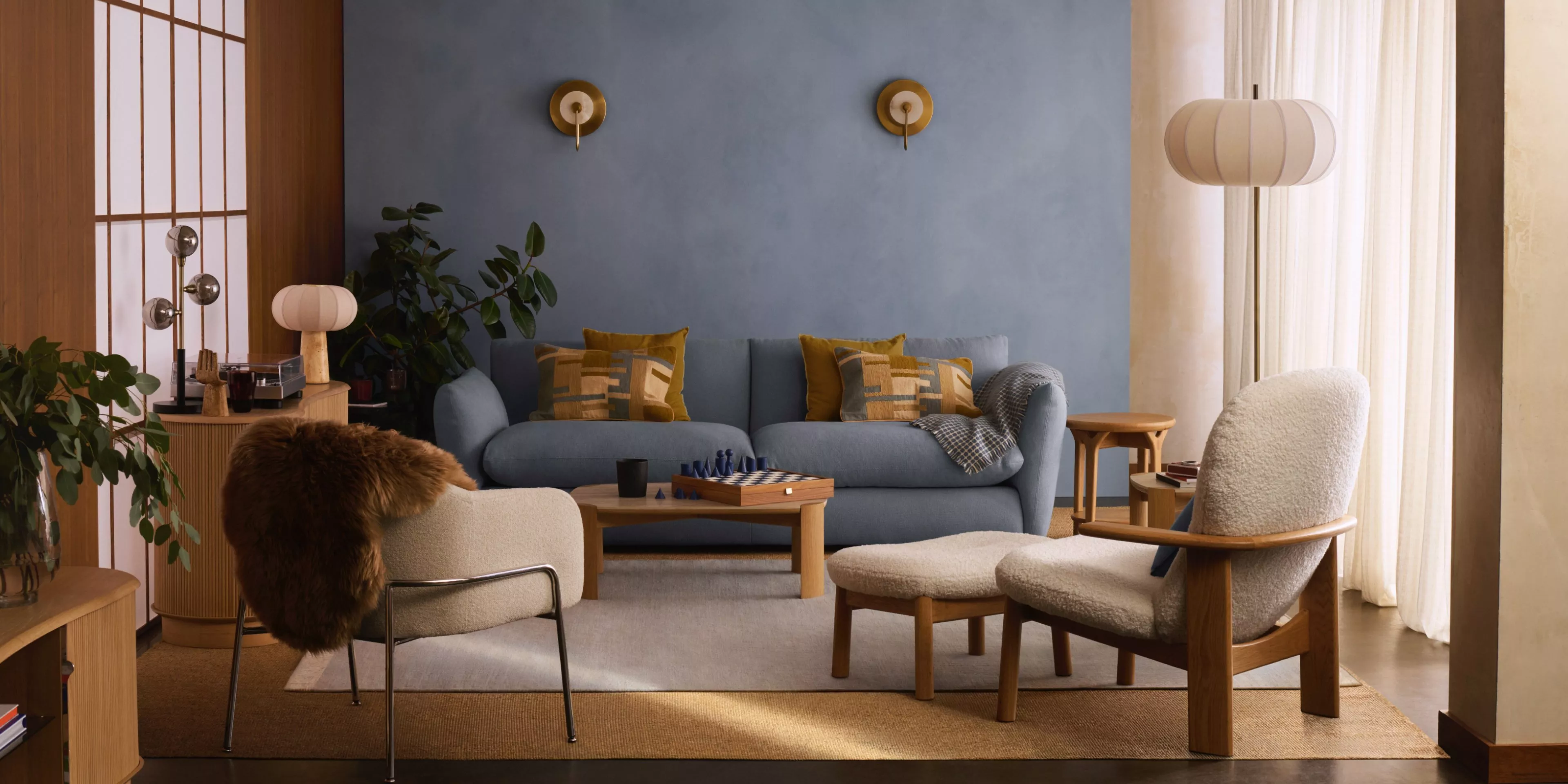 Scandi style modern living room with blue sofa, timber furniture, cosy armchairs, and warm natural light.