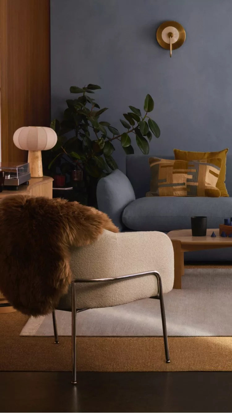 Scandi style modern living room with blue sofa, timber furniture, cosy armchairs, and warm natural light.