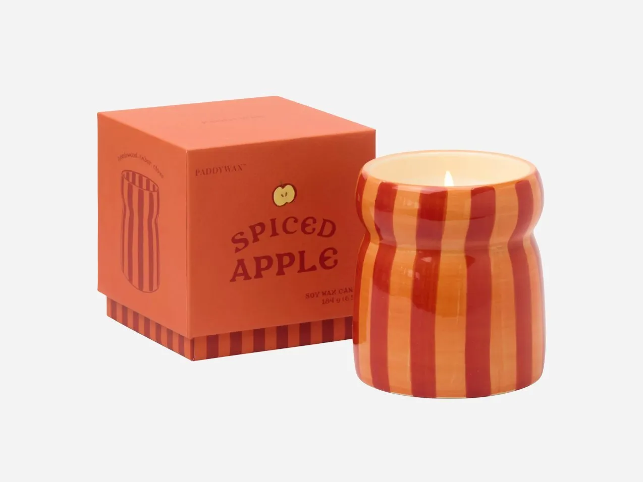 Paddywax Spiced Apple soy wax candle in striped ceramic jar with matching orange gift box, lit flame display