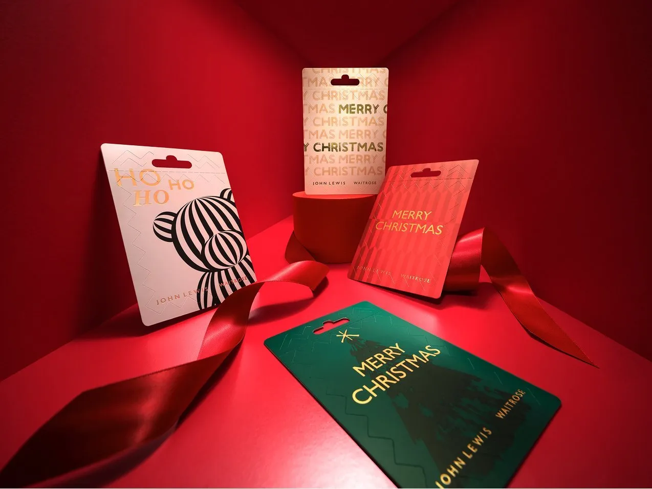 Christmas gift cards with festive designs on a red backdrop with ribbon, ideal for holiday gifting and shopping